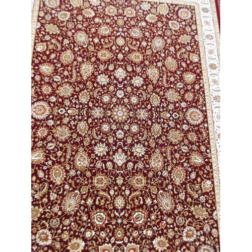 779 - A red ground woven silk carpet with all over traditional floral design, 63