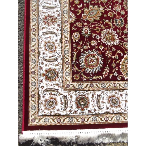 779 - A red ground woven silk carpet with all over traditional floral design, 63