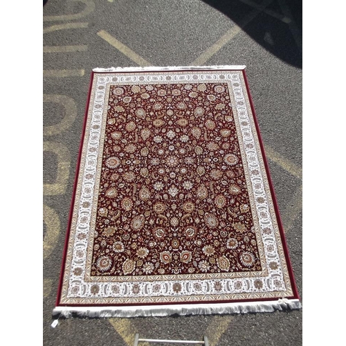 779 - A red ground woven silk carpet with all over traditional floral design, 63