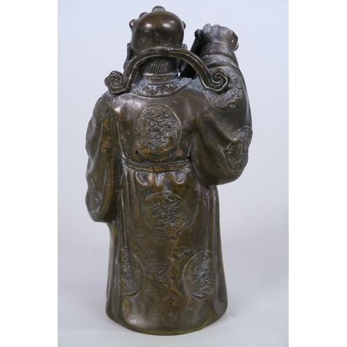 21 - A Chinese bronze figure of a smiling sage holding a scroll and libation cup, 6½