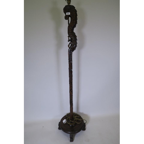 821 - A hardwood standard lamp carved in the form of a dragon, on circular base with four feet, 62