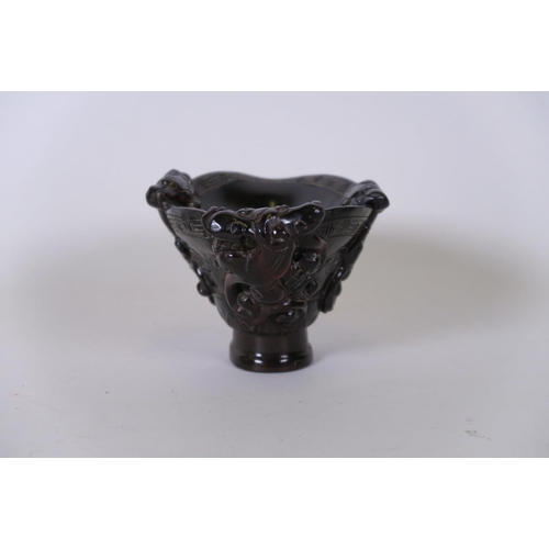 49 - A Chinese carved horn libation cup decorated with climbing kylin, carved mark to base, 5½