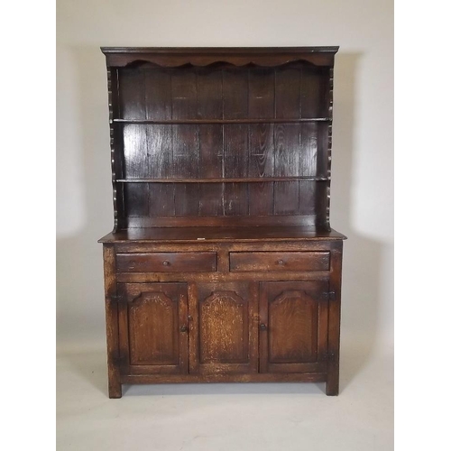 881 - A late C19th/early C20th oak dresser, the upper section with shaped ends and cornice with two shelve... 