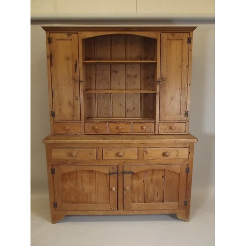 890 - A pine dresser, the upper section with two cupboards flanking shelves over five spice drawers, the b... 