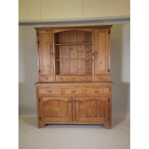 890 - A pine dresser, the upper section with two cupboards flanking shelves over five spice drawers, the b... 