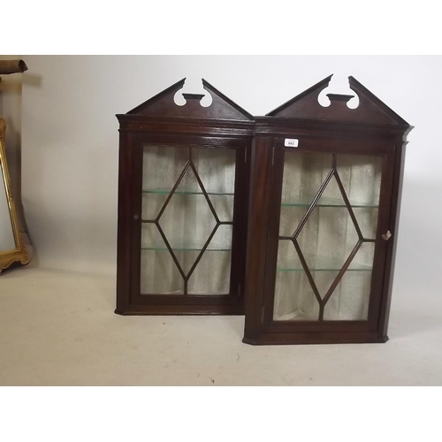 887 - A pair of late C19th mahogany corner cabinets with broken swan neck pediments over single astragal g... 