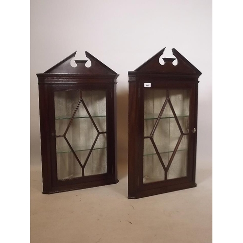 887 - A pair of late C19th mahogany corner cabinets with broken swan neck pediments over single astragal g... 