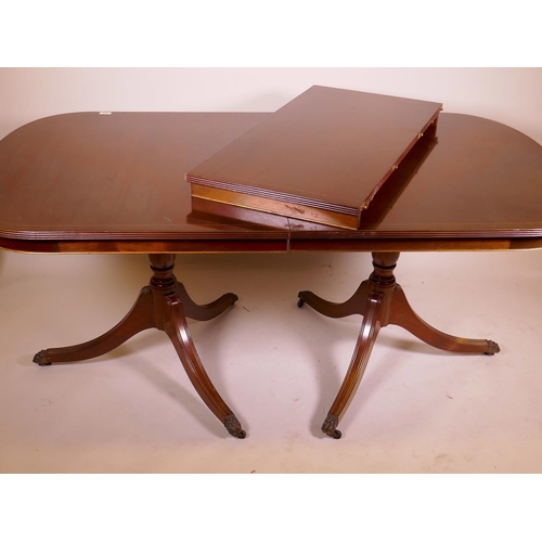 879 - A mahogany twin pedestal dining table with extra leaf, the reeded edge top with inlaid stringing, 36... 