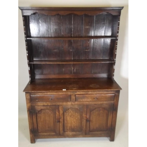 881 - A late C19th/early C20th oak dresser, the upper section with shaped ends and cornice with two shelve... 