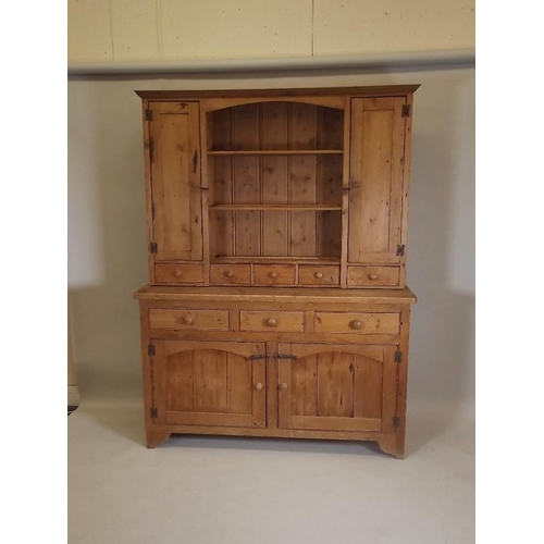 890 - A pine dresser, the upper section with two cupboards flanking shelves over five spice drawers, the b... 