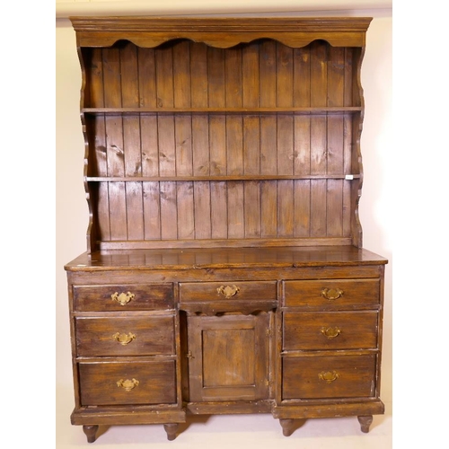 894 - A C19th polished pine dresser, with seven drawers and cupboard, a Delft rack above, raised on turned... 