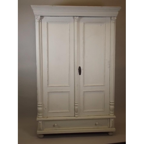 904 - A C19th painted pine armoire, with two panelled doors over a single drawer, and carved column decora... 