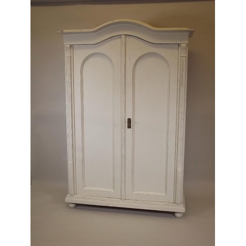 905 - A C19th painted pine armoire, with two arched doors and domed top, raised on bun feet, 49