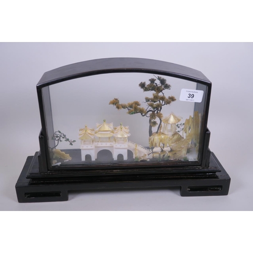 39 - An Oriental mother of pearl and abalone model of a lakeside temple, with trees and cranes, in a glas... 