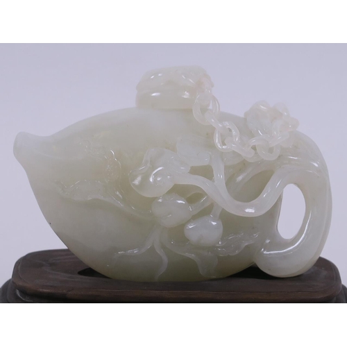 50 - A Chinese  white jade teapot with finely carved peach and ruyi decoration, mounted on a carved hardw... 