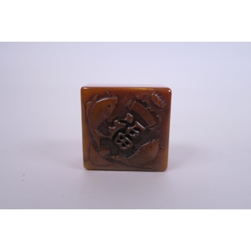 41 - A Chinese amber soapstone seal, with carved carp and character decoration to top, 2