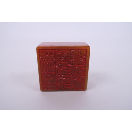 41 - A Chinese amber soapstone seal, with carved carp and character decoration to top, 2