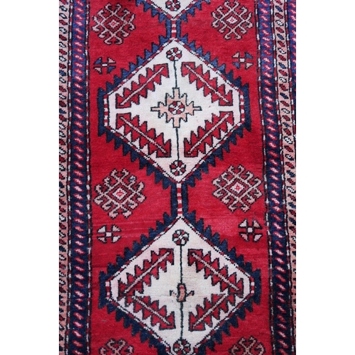 1165 - A Persian red and blue ground wool runner, with medallion design decoration, 39