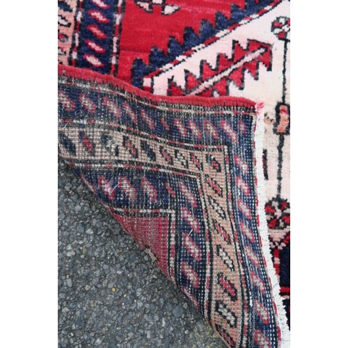 1165 - A Persian red and blue ground wool runner, with medallion design decoration, 39