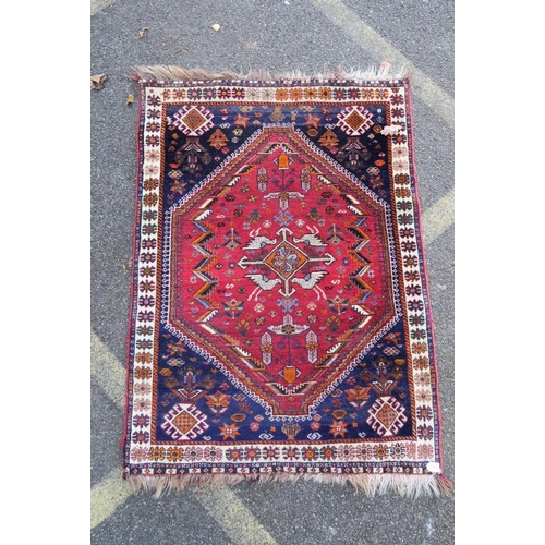 1172 - A Persian red and blue ground rug with bird and central medallion decoration, 42