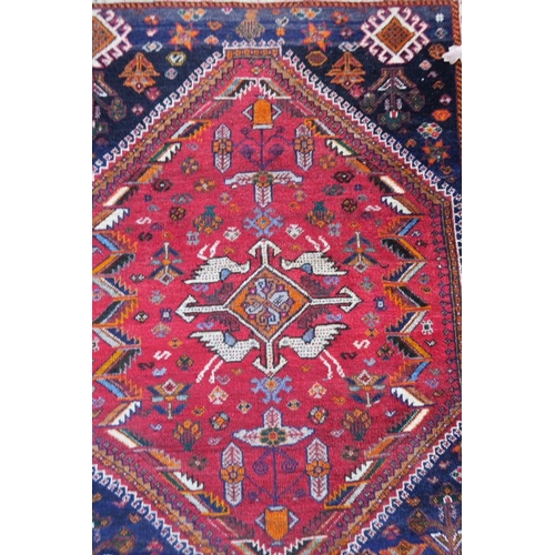 1172 - A Persian red and blue ground rug with bird and central medallion decoration, 42