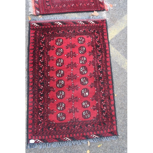 1173 - A Persian red ground Bokhara rug, together with two small and another red ground Persian rug, A/F ho... 