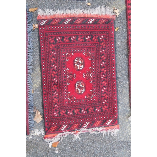 1173 - A Persian red ground Bokhara rug, together with two small and another red ground Persian rug, A/F ho... 