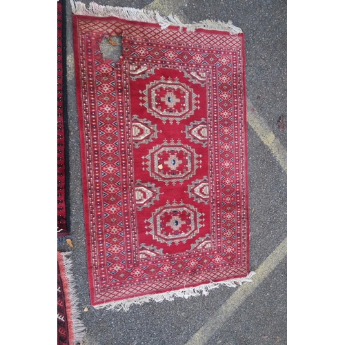 1173 - A Persian red ground Bokhara rug, together with two small and another red ground Persian rug, A/F ho... 