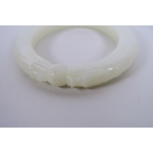 53 - A Chinese carved white jade bangle with dragon head decoration, 3