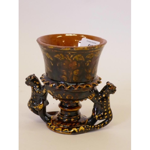 57 - A slipware pottery goblet with polychrome floral decoration and leopard handles, 5