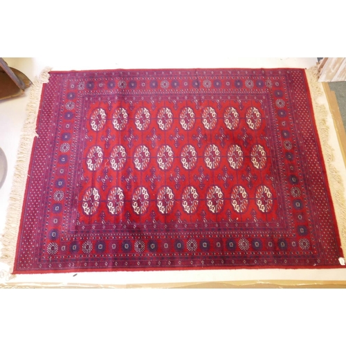 1205 - A Persian style red ground carpet with Bokhara decoration, 55