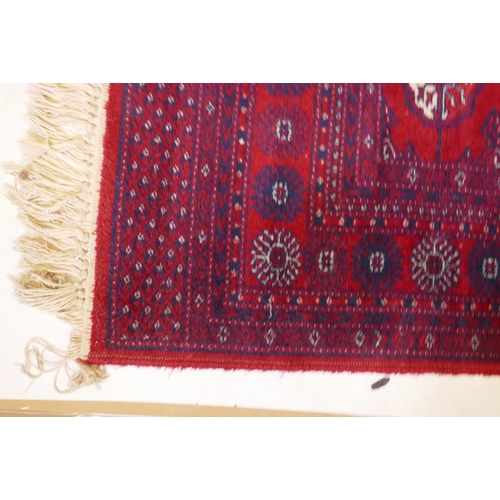 1205 - A Persian style red ground carpet with Bokhara decoration, 55