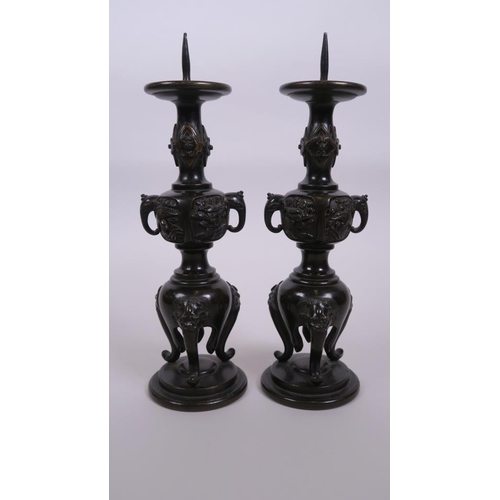 40 - A pair of C19th Japanese  bronze candlesticks with two elephant mask handles and raised decoration o... 