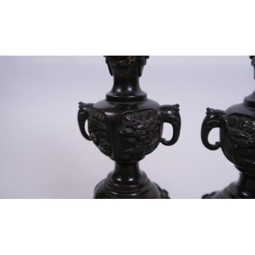 40 - A pair of C19th Japanese  bronze candlesticks with two elephant mask handles and raised decoration o... 