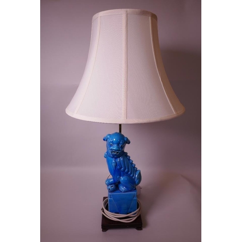 26 - An Oriental porcelain table lamp, the wooden base mounted with a blue glazed porcelain figurine of a... 