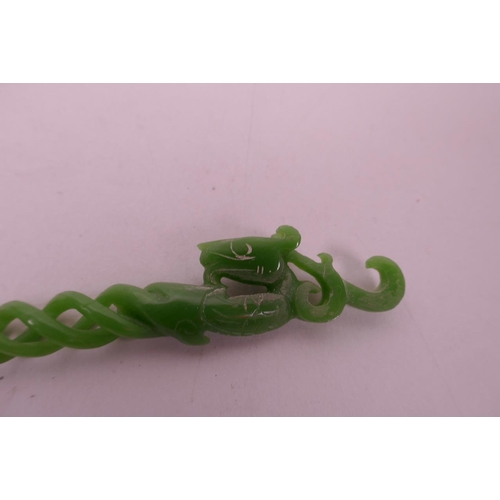 39 - A Chinese green hardstone hairpin with carved spiral decoration to stem and dragon head to end, 9½