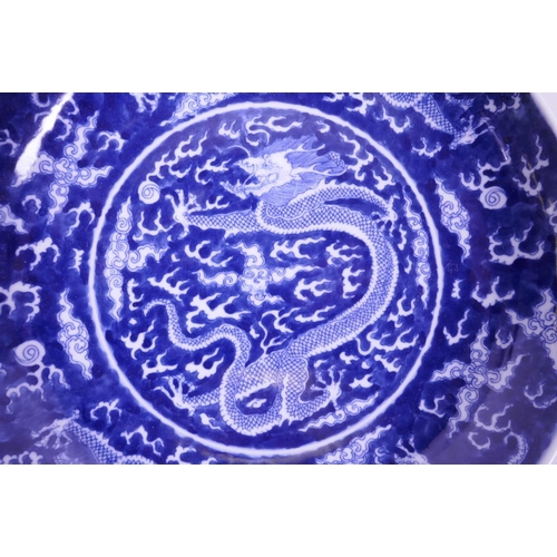 55 - A Chinese blue and white porcelain charger decorated with dragons chasing the flaming pearl, 6 chara... 