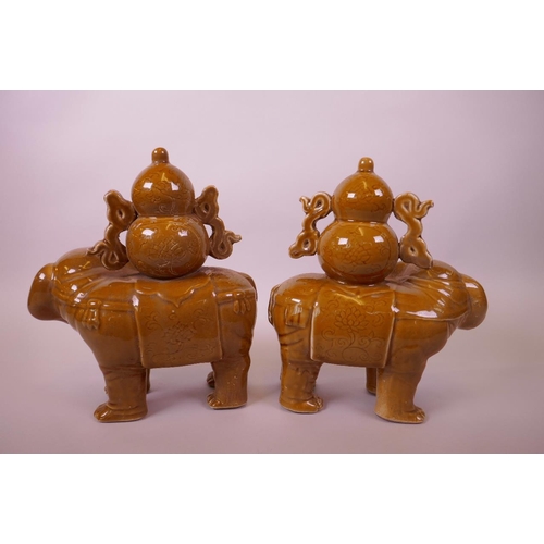 25 - A pair of ochre glazed pottery elephants carrying double gourds, indistinct marks to base, 9