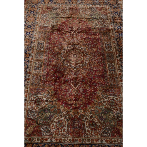 1221 - An Oriental carpet with blue borders and floral designs on a red field, 60