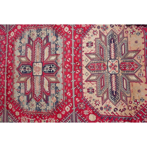 1219 - A red ground Persian style rug with a triple medallion decoration and blue border, 120