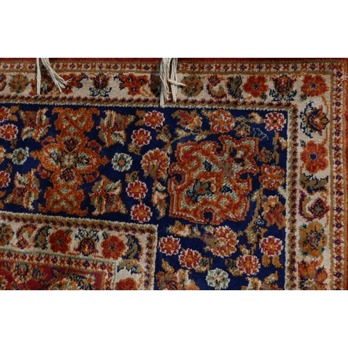 1221 - An Oriental carpet with blue borders and floral designs on a red field, 60