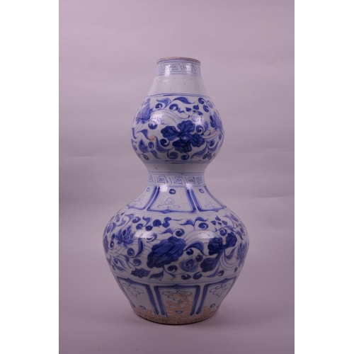 125 - A Chinese Ming style blue and white pottery double gourd vase with lotus flower decoration, 13½