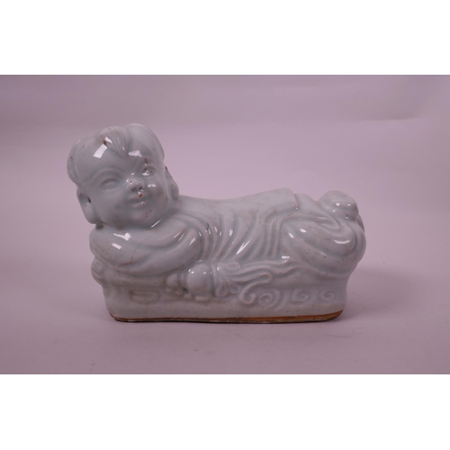 20 - A Chinese celadon glazed pottery pillow in the form of a child, impressed seal mark to base, 8½