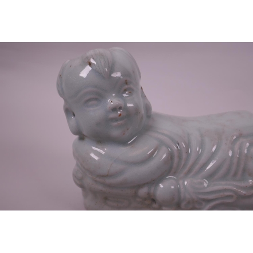 20 - A Chinese celadon glazed pottery pillow in the form of a child, impressed seal mark to base, 8½