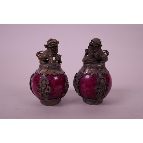 31 - A pair of Chinese white metal bound red hardstone scroll weights, decorated with kylin knops, 3