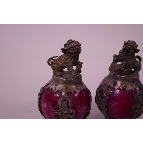 31 - A pair of Chinese white metal bound red hardstone scroll weights, decorated with kylin knops, 3