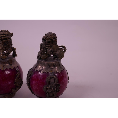 31 - A pair of Chinese white metal bound red hardstone scroll weights, decorated with kylin knops, 3