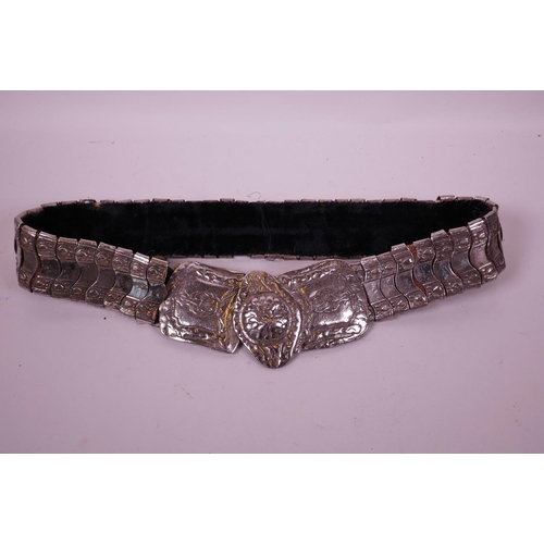 82 - An Indian silvered metal belt with raised floral decoration to buckle, 36