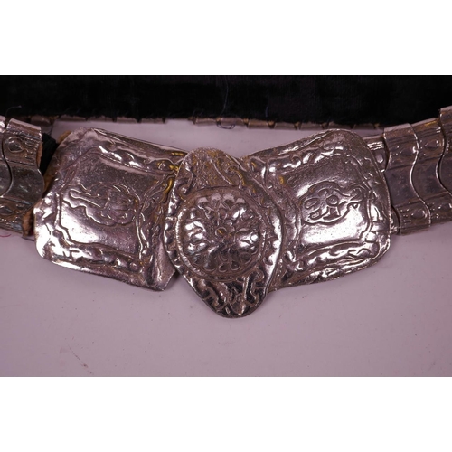 82 - An Indian silvered metal belt with raised floral decoration to buckle, 36