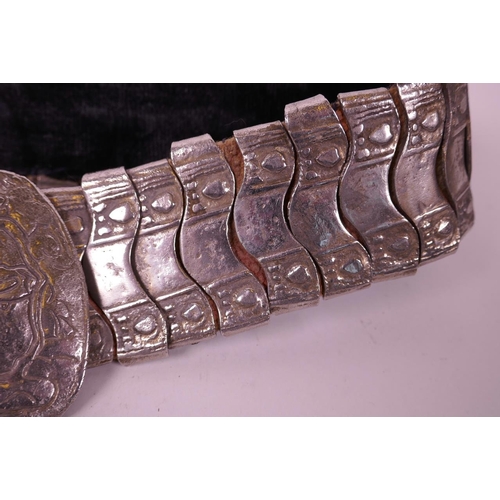 82 - An Indian silvered metal belt with raised floral decoration to buckle, 36